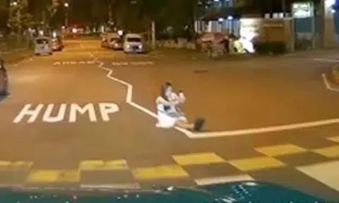 Woman risks her life by sitting in the middle of the road to take a selfie