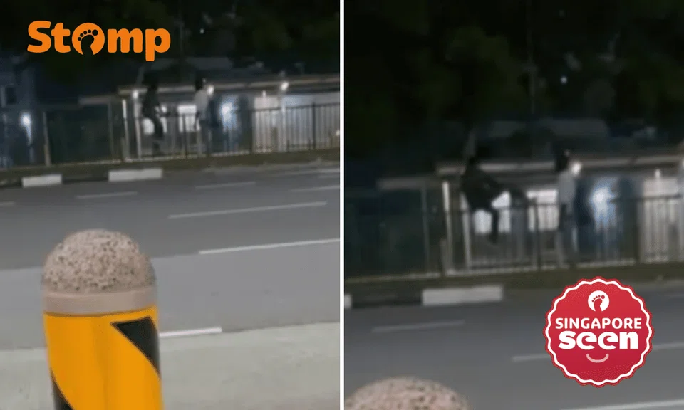 two men climb over road divider