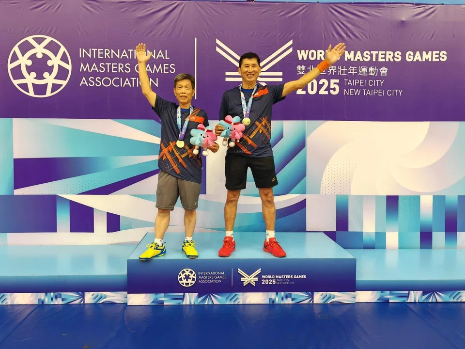 Singapore’s Victor Sim (right) and his badminton men’s doubles 70+ partner Yang Zhen Xing on the podium after clinching gold.