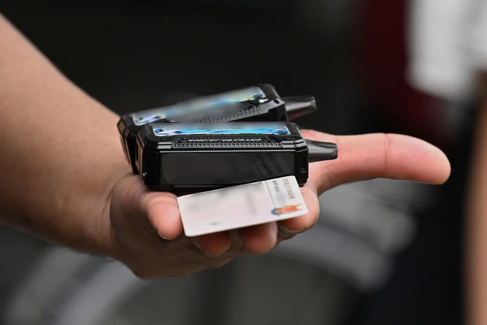 An HSA officer holding confiscated vapes and a suspect’s identity card during enforcement operations in Tampines on July 14.