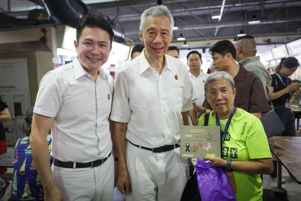 Madam Soh Siew Geok with her autograph book alongside PAP candidate for Kebun Baru SMC Henry Kwek and Senior Minister Lee Hsien Loong.
