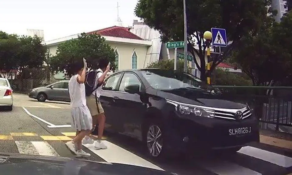 Students raise hands while crossing road... but have close call with driver who speeds past them