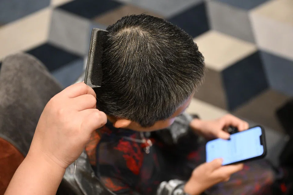 Ms Lim having her hair styled while she takes a quick break to check her phone.