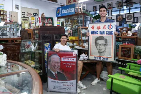 Mr Wak Sadri (left), owner of Treasure At Home, with his son Emyr Uzayr, holding election posters of Dr Tan Cheng Bock and Mr Wong Kan Seng at Treasure At Home Vintage Store at 80 Playfair Road. 