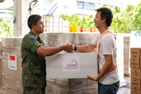 A Caritas Humanitarian Aid and Relief Initiatives Singapore representative (right) handing over humanitarian aid to the SAF's Changi RHCC representative.
