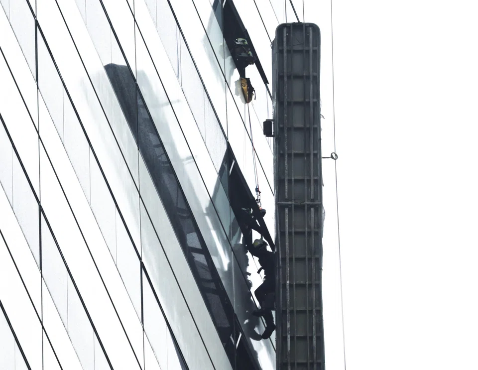 A gondola was seen supported by a cable only on one side and hanging from the exterior of the building.