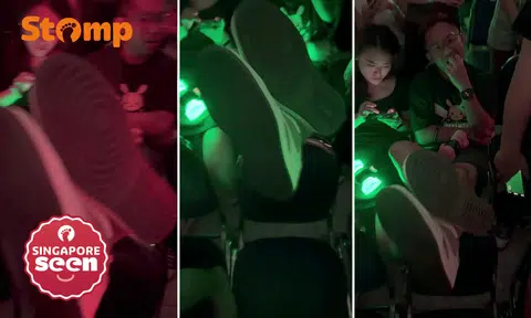 Audience member props feet up on back of another concertgoer's seat
