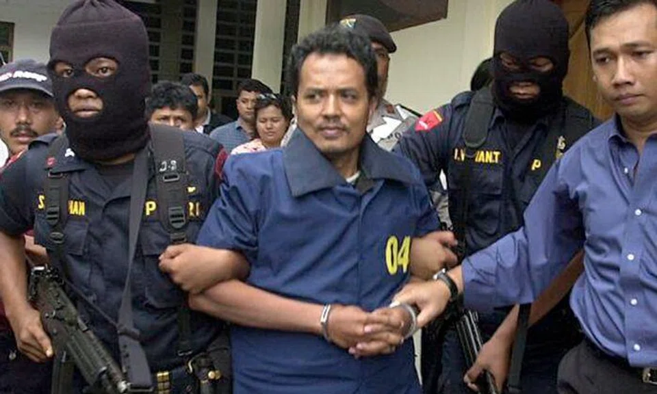 Mas Selamat Kastari (centre) leaving the Tanjung Pinang police station under heavy guard in 2003. PHOTO: ST FILE