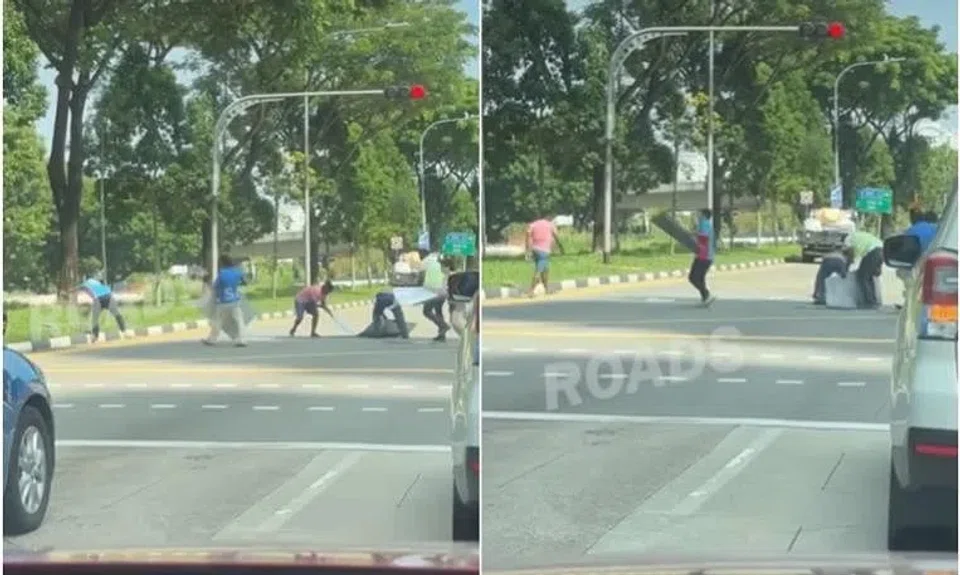 Eight different individuals can be seen running towards the pile of items on the road and scrambling to clear it before the traffic light turns green. 