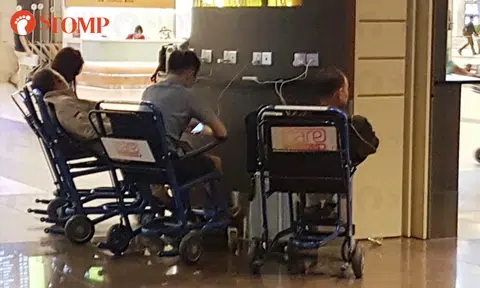 Visitors sit on wheelchairs to use charging ports at Changi Airport T2