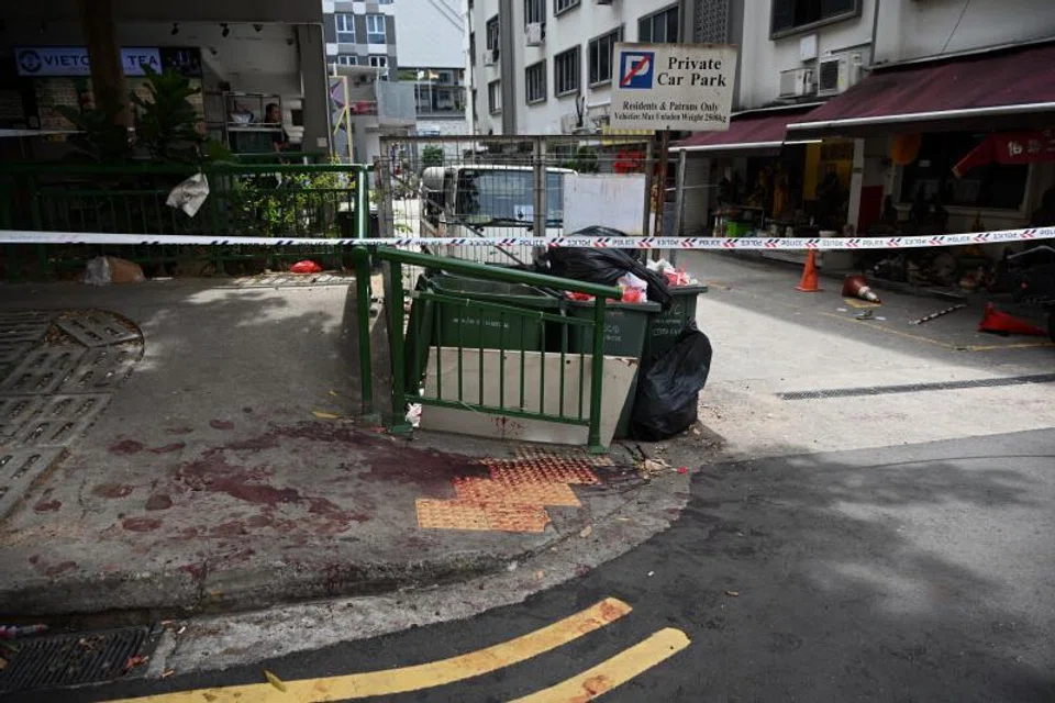 Bloodstains on the pavement near a bin area, close to a Buddhist temple.