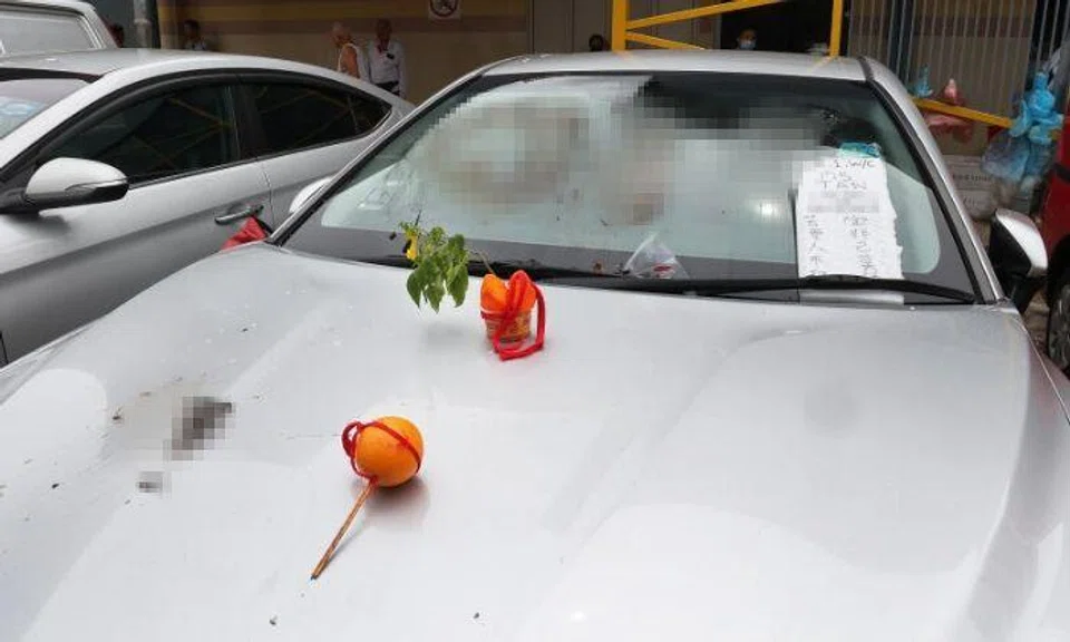 A chicken seller's car was smeared with poop in the carpark near Sims Vista Market & Food Centre in Aljunied. A cake with a flower stuck in it as well as an orange with a red string and two joss sticks were also on the car's bonnet.