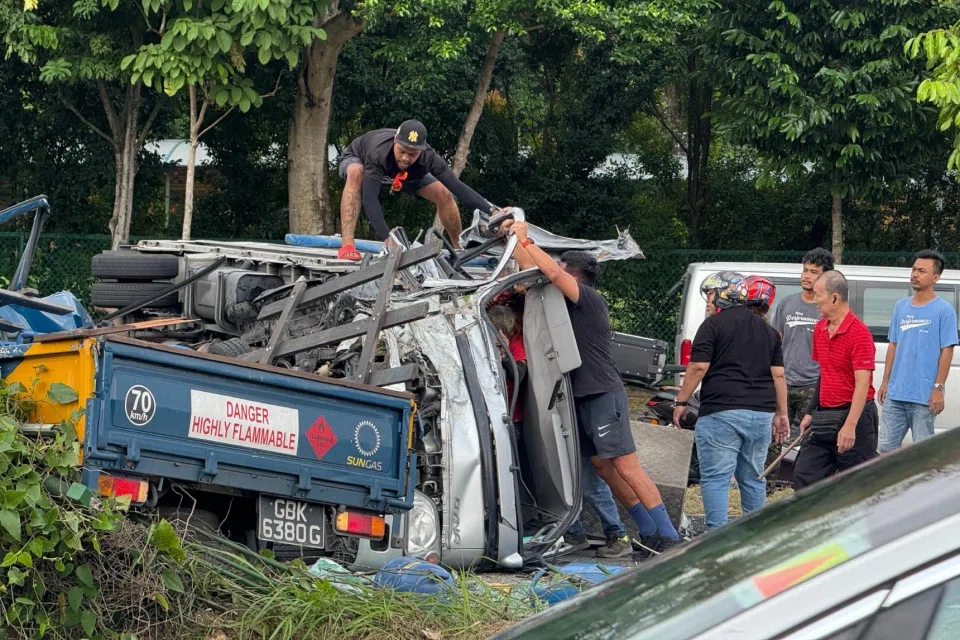 Mr Addy Izwan (pictured on top of the lorry) tries unsuccessfully to open the door of a lorry on its side on May 27.