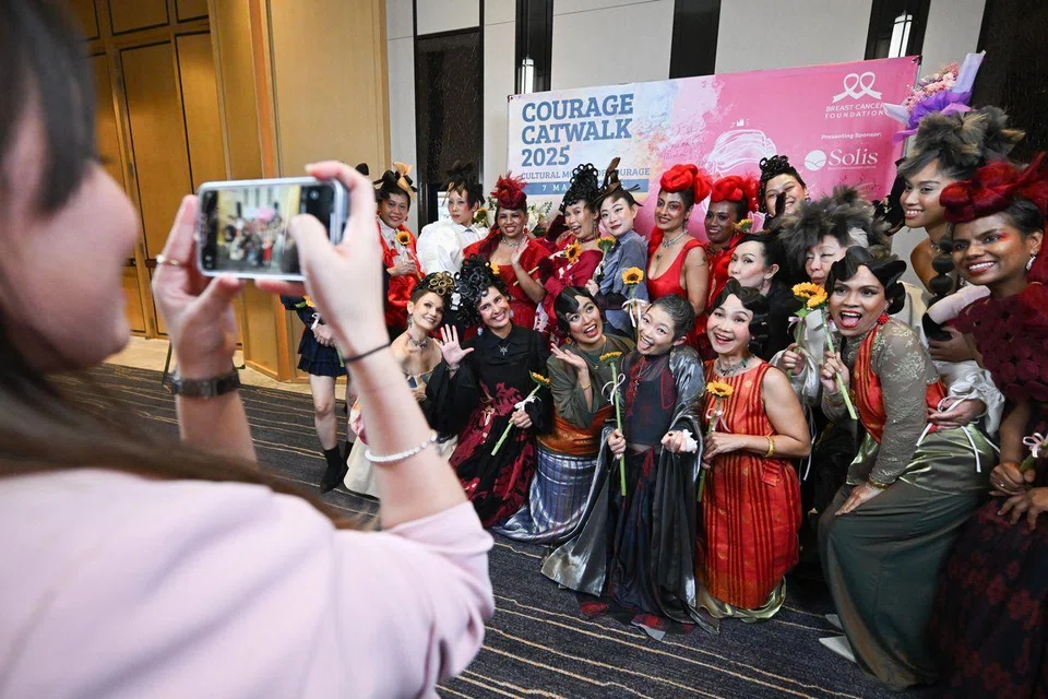 Ms Lim having her photo taken with the other “pink warriors” who strutted down the runway in vibrant costumes.