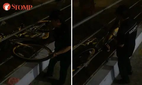 Man in security uniform shoves oBike between platform railings and lets it fall