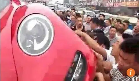 Enraged crowd tip over car in China after driver slaps jaywalker