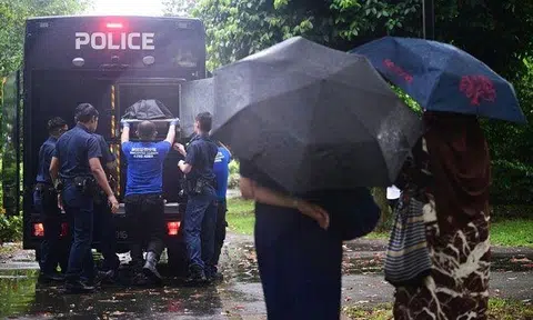 Family members watching as the man’s body is carried into a police hearse on Nov 7. ST PHOTO: AZMI ATHNI