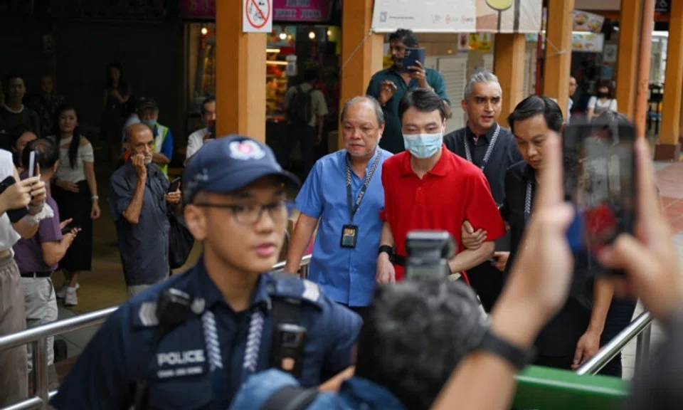 Flanked by six police officers, Chinese national Wu Tao returned at around 9am to the stall he was reportedly working at in Maxwell Food Centre.