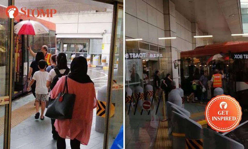 Kind employee shelters passengers with umbrella during rainy day at Toa Payoh Bus Interchange