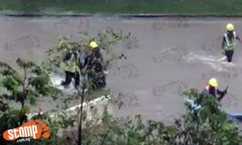 Workers wade through shin-deep water after heavy rain causes flood at Hougang