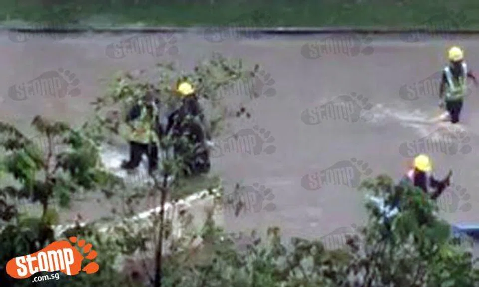 Workers wade through shin-deep water after heavy rain causes flood at Hougang