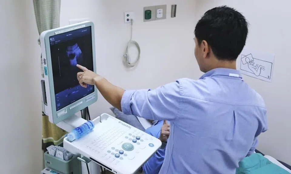Dr Tan Yu Guang using an ultrasound scan to show patient Tony Wong (not his real name) that the cancer in his bladder is gone.