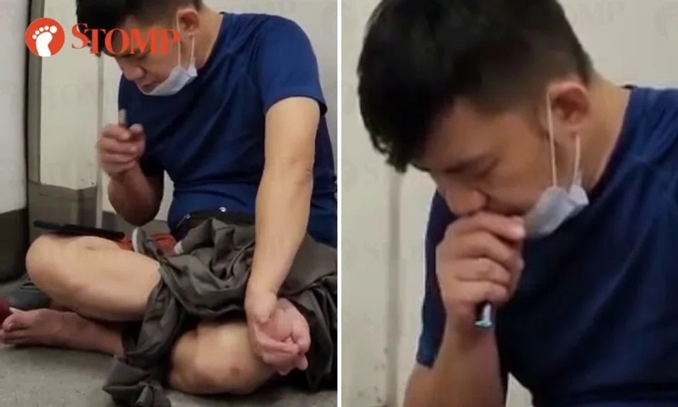 The video shows the man wearing his mask under his chin with his left hand on the toes of his left foot and his other hand holding an e-vaporiser.