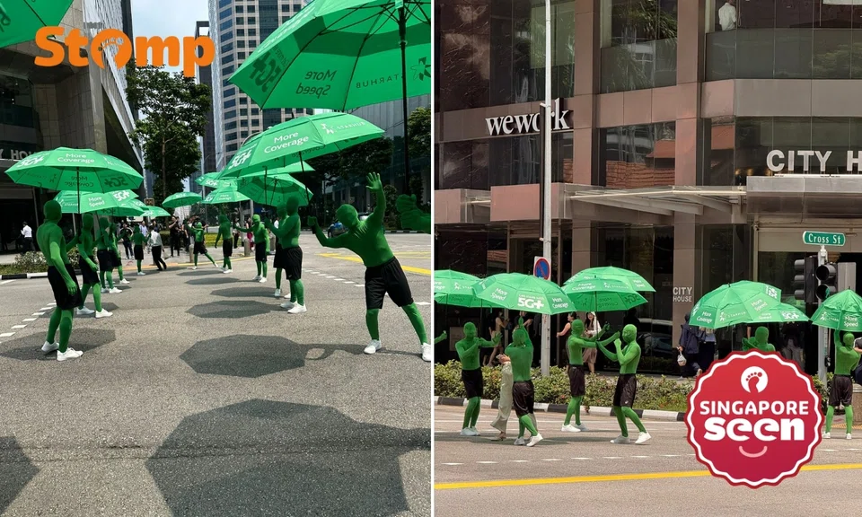 ‘Green men’ hold up umbrellas for people at Lau Pa Sat