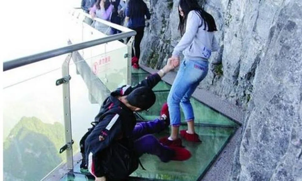 Man so petrified by glass walkway on China mountain, GF has to drag him along