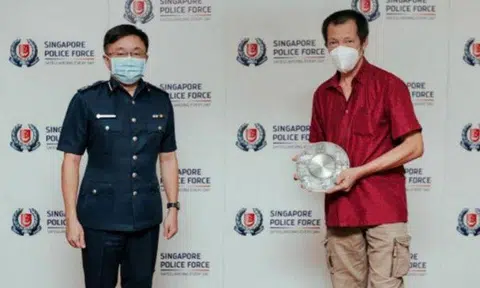 Mr Goh Wui Teck (right) is awarded the Public Spiritedness Award by Assistant Commissioner of Police Marc E, on Feb 24, 2022. PHOTO: SINGAPORE POLICE FORCE