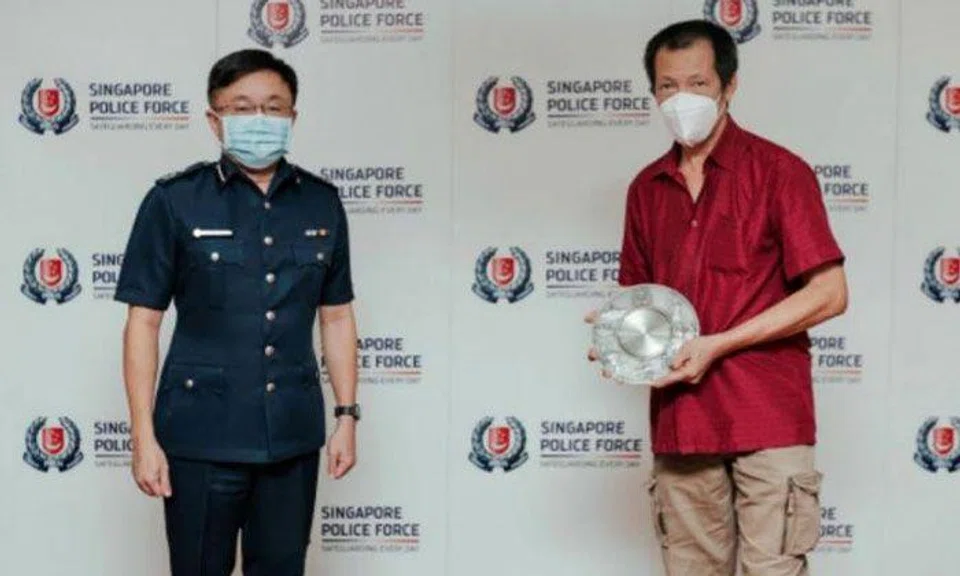 Mr Goh Wui Teck (right) is awarded the Public Spiritedness Award by Assistant Commissioner of Police Marc E, on Feb 24, 2022. PHOTO: SINGAPORE POLICE FORCE