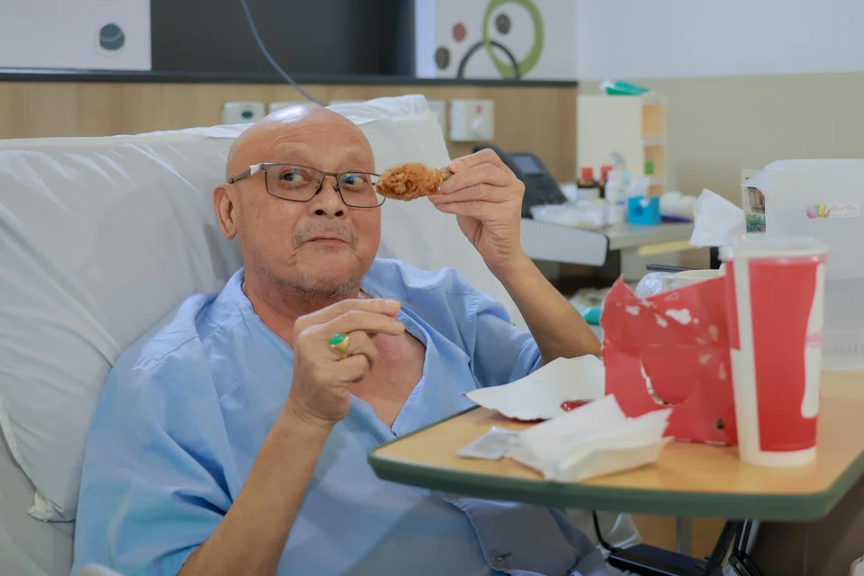 Assisi Hospice patient Yeo Kok Hoong, who has lung and brain cancer, enjoying the fried chicken he requested.