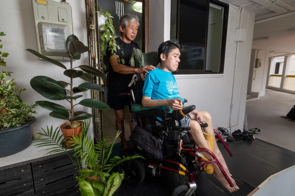 Mr Steven Eng pushing Mr William Eng in his wheelchair out of their HDB flat in Tampines.
