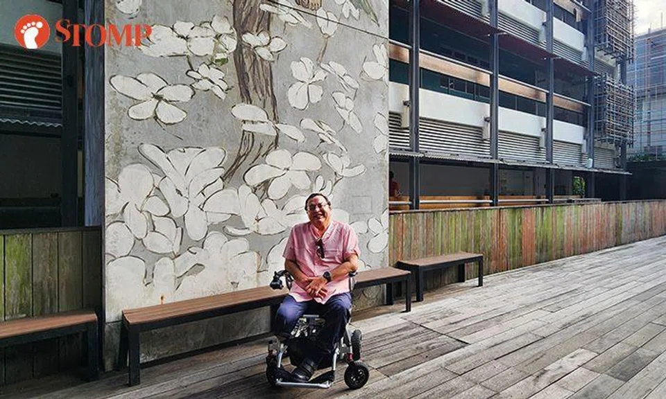 Sheldon in front of a hand-painted mural in Enabling Village.