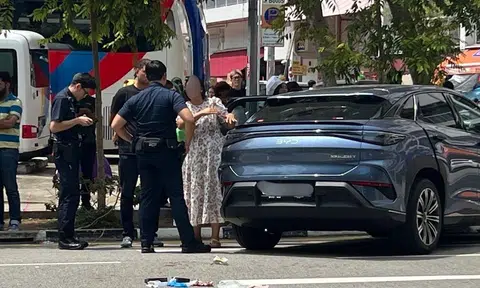 A woman in a floral dress is seen gesturing towards the man.