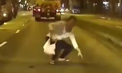 Woman runs across road and towards car, crouches down -- then suddenly changes her mind