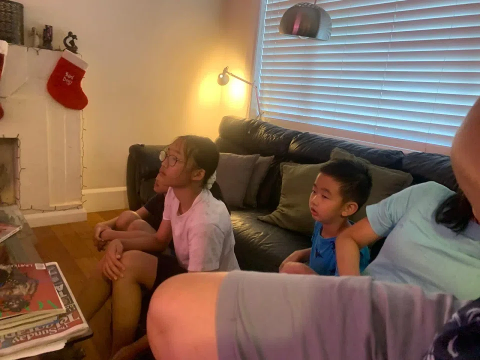 Members of Ms Karin Lee's family watching the news on TV at the home of a local couple who offered them refuge for updates of the Bondi Beach shooting. PHOTO: COURTESY OF KARIN LEE