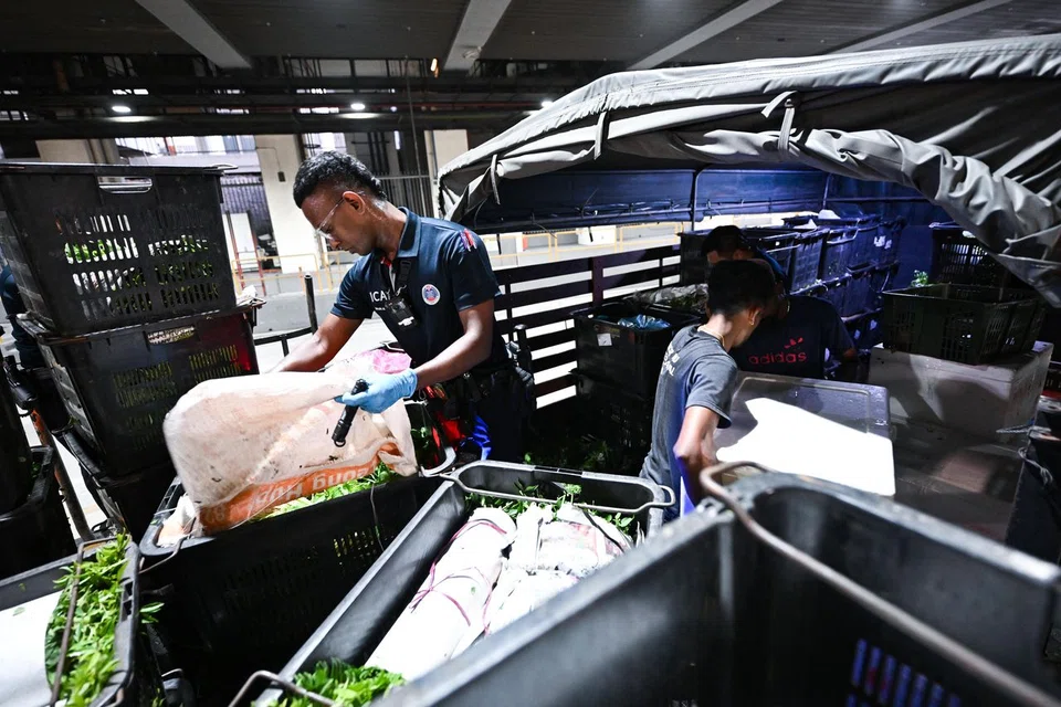 Sergeant 2 Daniyal Na'im Mohamed Azaman (left) conducting a vehicle search at the Arrival Cargo Zone at Woodlands Checkpoint on Aug 4.