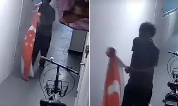 man walking home with giant s’pore flag tied to pole