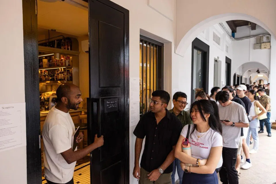 Mr Theeviyan Raja (left), a front-of-house staff member at Scarpetta, welcomes diners as the restaurant opens for dinner. By 6pm, around 80 customers had joined the queue.