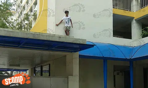 Young Spiderman-wannabe saunters on walkway shelter at Toa Payoh Lor 1 as friend looks on