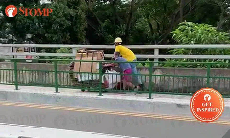 Construction worker helps elderly woman to push cardboard cart in Potong Pasir