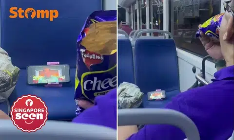 Man watches movie and snacks on Cheezels on bus