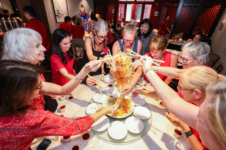 American Women's Association members tossing yusheng at a restaurant during a guided heritage tour of Chinatown on Feb 13. ST PHOTO: BRIAN TEO
