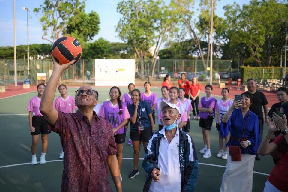President Tharman Shanmugaratnam throwing a netball at the Kallang ActiveSG Netball Centre on May 28. Looking on are President Tharman's spouse, Ms Jane Ittogi (right), members of NorthLight School's netball team and their coach Liew Hin Joon (foreground).