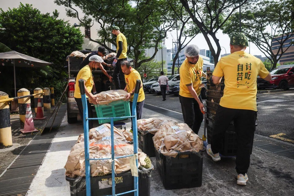 Workers unloading durians from a truck at 99 Old Trees Durian parlour in Outram. 