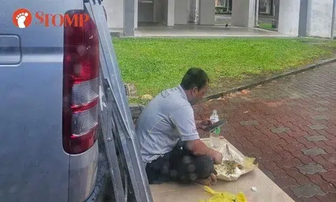 Stomper Anna shared a photo of the worker sitting on cardboard behind a parked van and using the rear door of the vehicle to shelter from the rain near Block 106A Canberra Road.