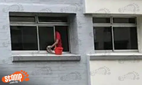 Look out below! Maid cleans window with bucket placed dangerously close to edge at Woodlands Block 367