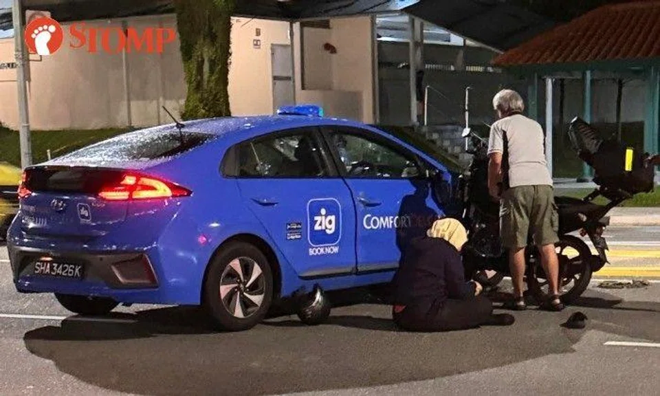 Stomper G shared photos of the accident's aftermath, showing a woman sitting on the road next to a blue Comfort DelGro taxi and a motorcycle in front of Block 304 Serangoon Avenue 2.