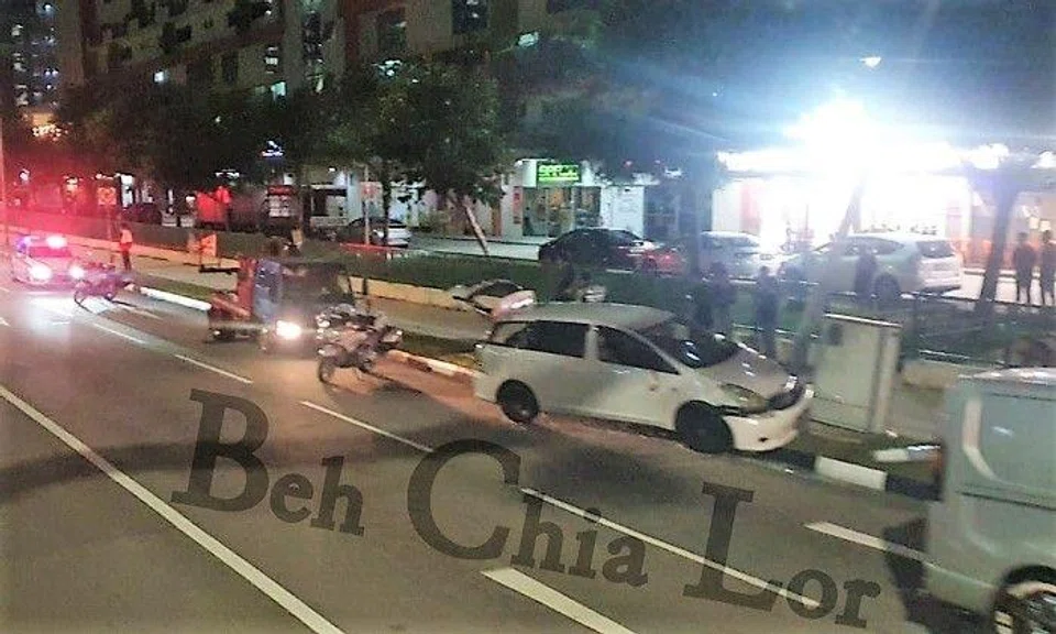 Photos posted on Facebook page Beh Chia Lor – Singapore Road show a white car smashed against a lamp post on a sidewalk, with its bumper dislodged.